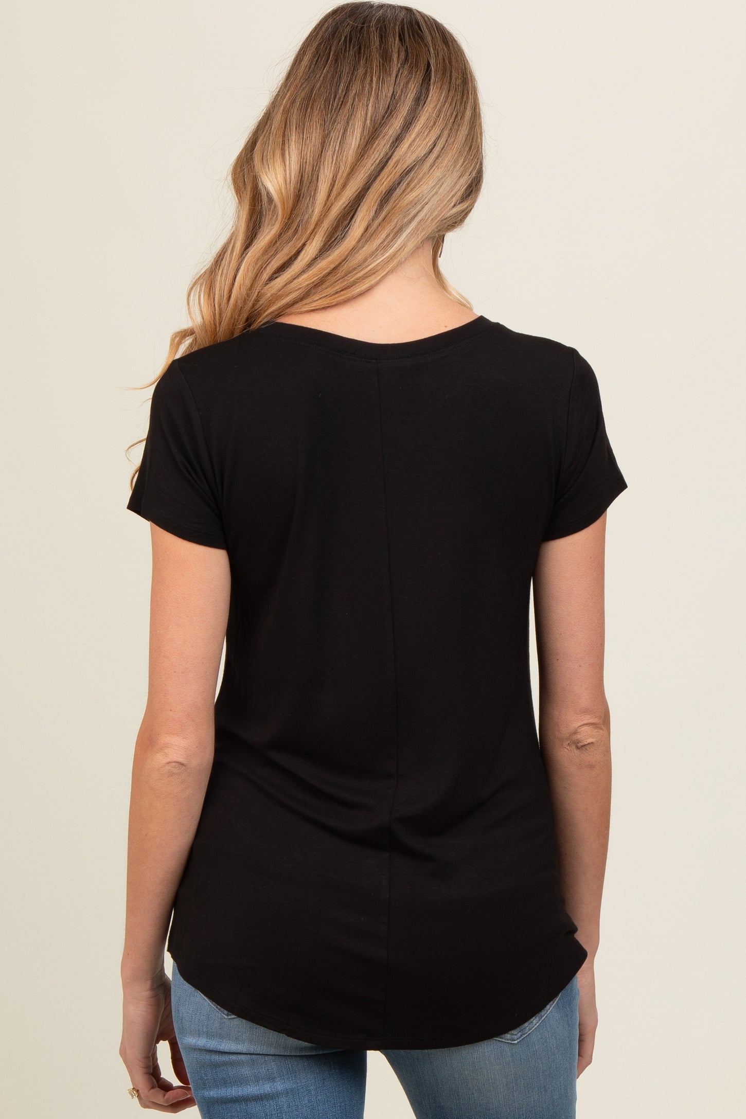 woman wearing a black short sleeve maternity top, viewed from the back, with a curved hemline and relaxed fit