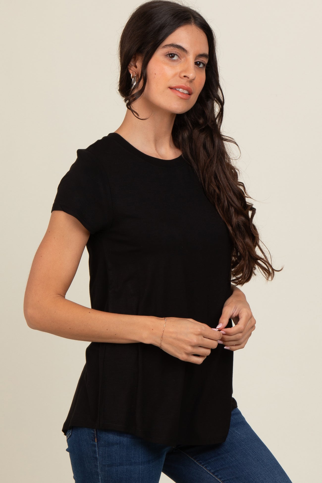 woman wearing a black short sleeve t-shirt with a relaxed fit, standing confidently and smiling