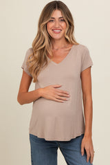 woman wearing a taupe v-neck maternity top and holding her baby bump