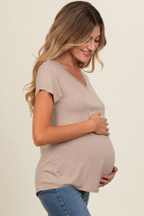 woman wearing a taupe short sleeve maternity top and holding her baby bump