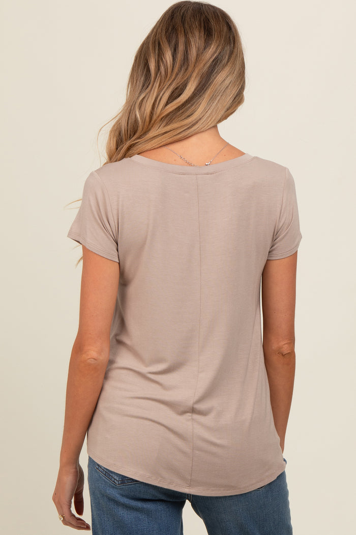 woman wearing a taupe short sleeve maternity top, seen from the back, paired with blue jeans