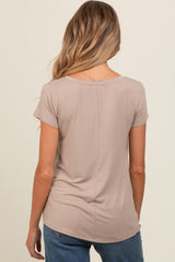 woman wearing a taupe short sleeve maternity top, seen from the back, paired with blue jeans