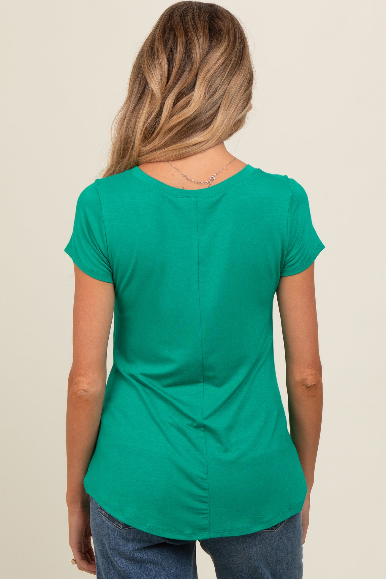 woman wearing a green short sleeve maternity top with a curved hem and back seam details