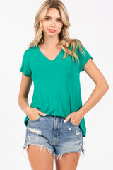 woman wearing a green v-neck t-shirt and distressed denim shorts with hands in pockets