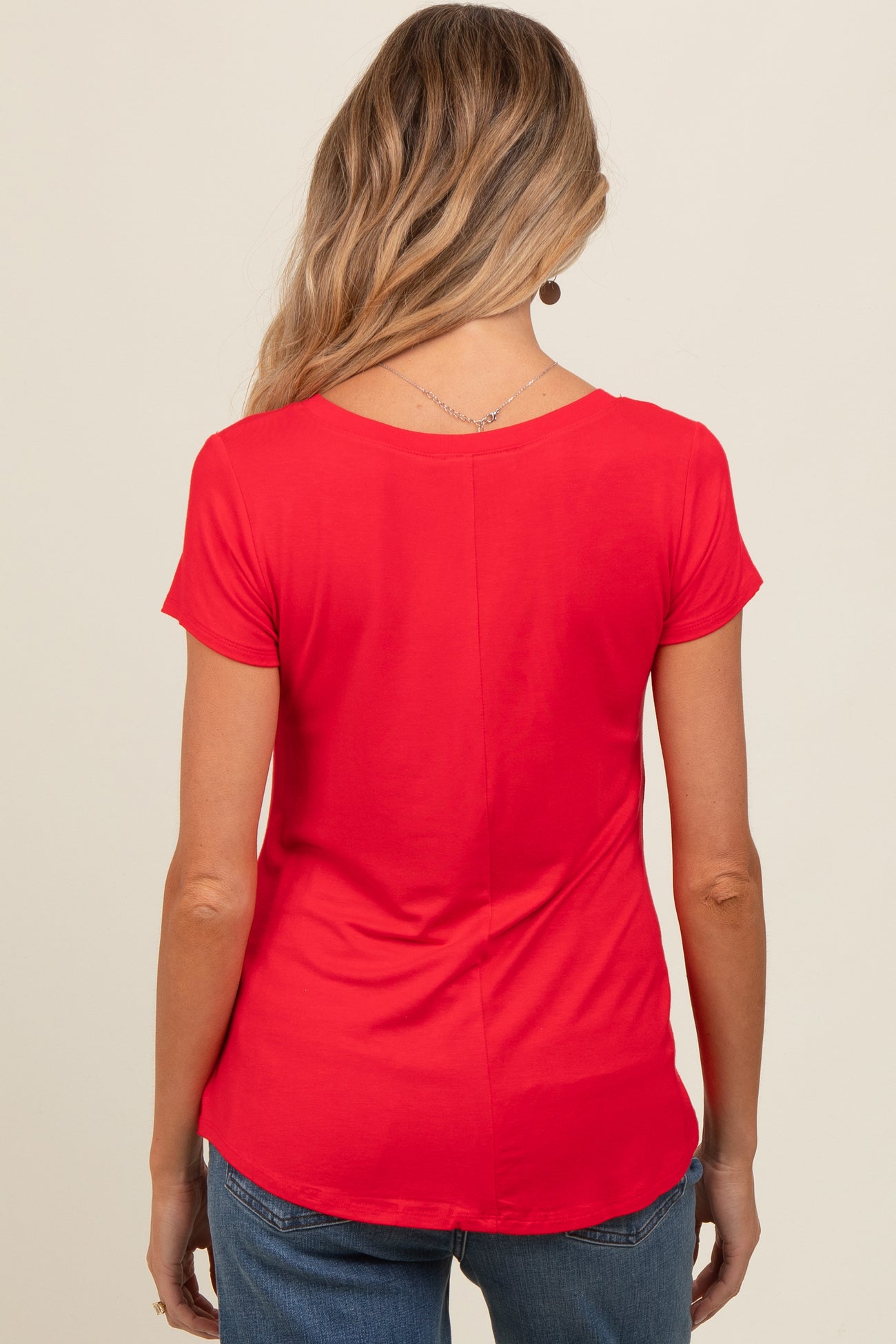 woman wearing a red short sleeve maternity top, seen from the back, with a curved hemline and relaxed fit