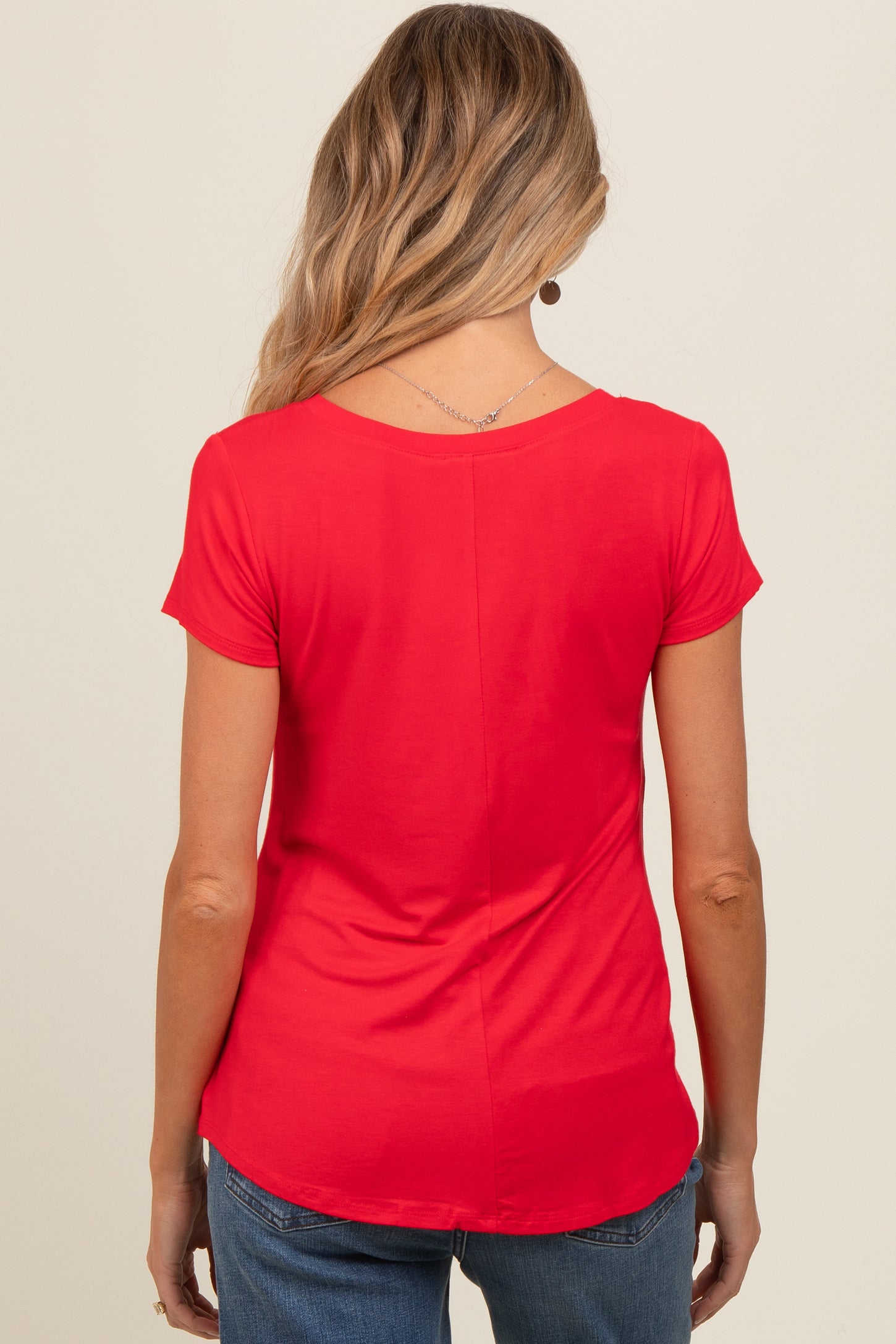woman wearing a red short sleeve maternity top, seen from the back, with a curved hemline and relaxed fit