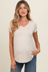 woman wearing a beige short sleeve maternity top with a v-neck and a baby bump visible