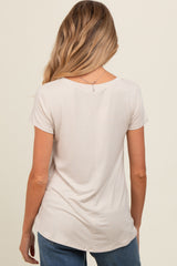 woman wearing a light beige short sleeve maternity top, shown from the back with a relaxed fit