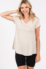 woman wearing a light beige short sleeve v-neck top with a flowy hem and black bike shorts