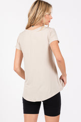 woman wearing a beige short sleeve top with a curved hem and a relaxed fit, styled with black shorts