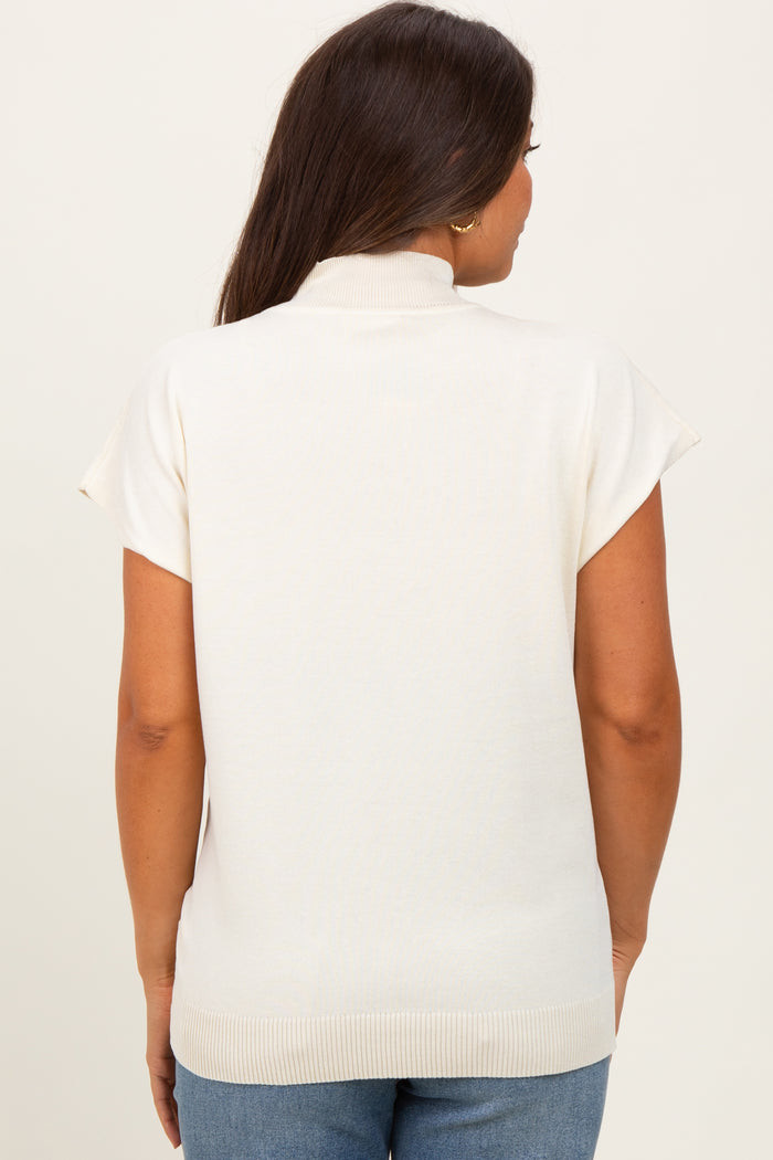 woman wearing a cream short sleeve maternity sweater with a mock neck, showing the back view
