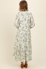woman wearing a long green floral maxi dress with puff sleeves and a tiered skirt, viewed from the back
