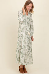 woman wearing a long sleeve green floral maxi dress with tiered detailing and a tassel tie neckline