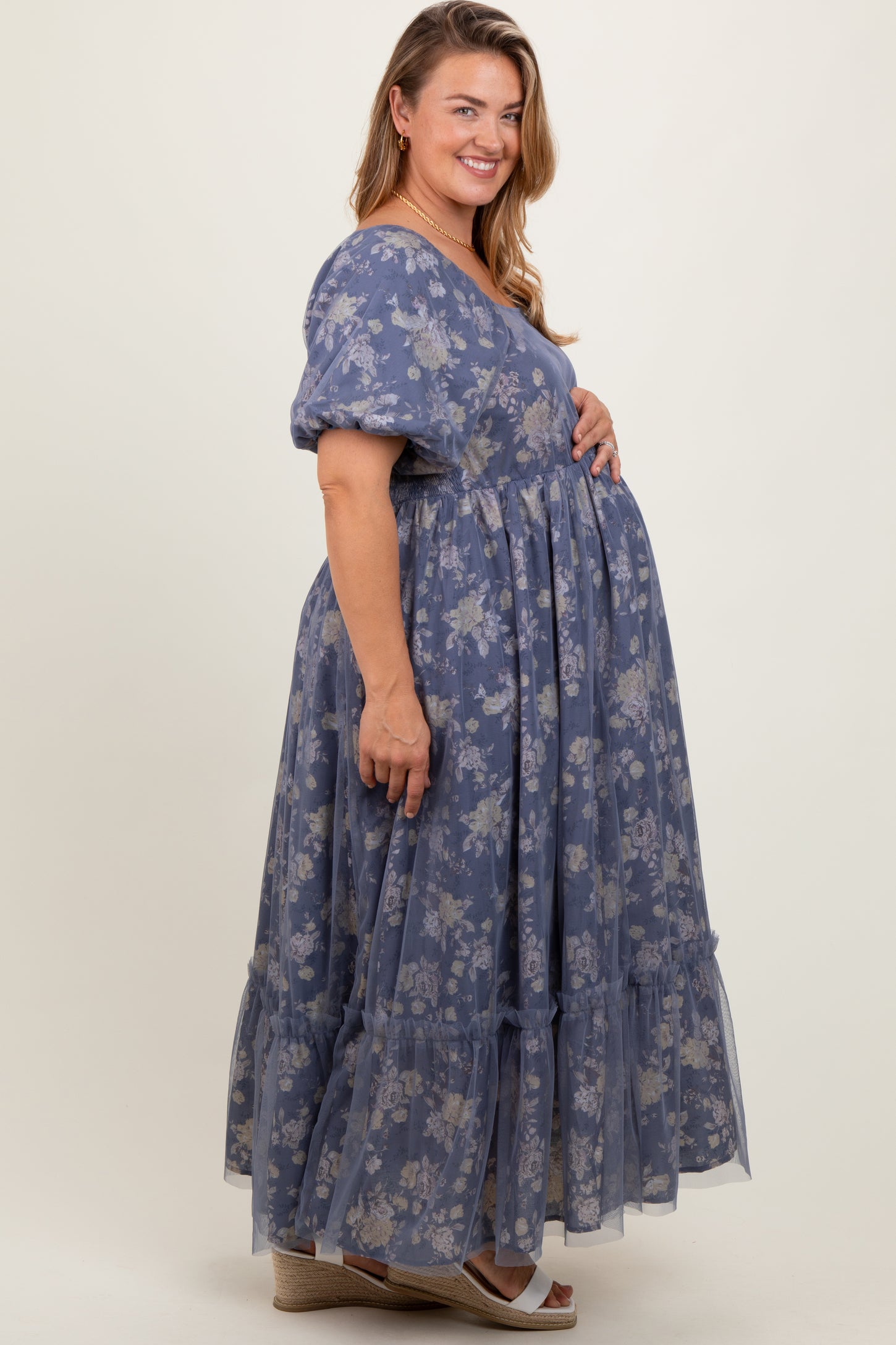 woman wearing a blue floral maternity maxi dress, showing her baby bump with a tiered ruffle hem