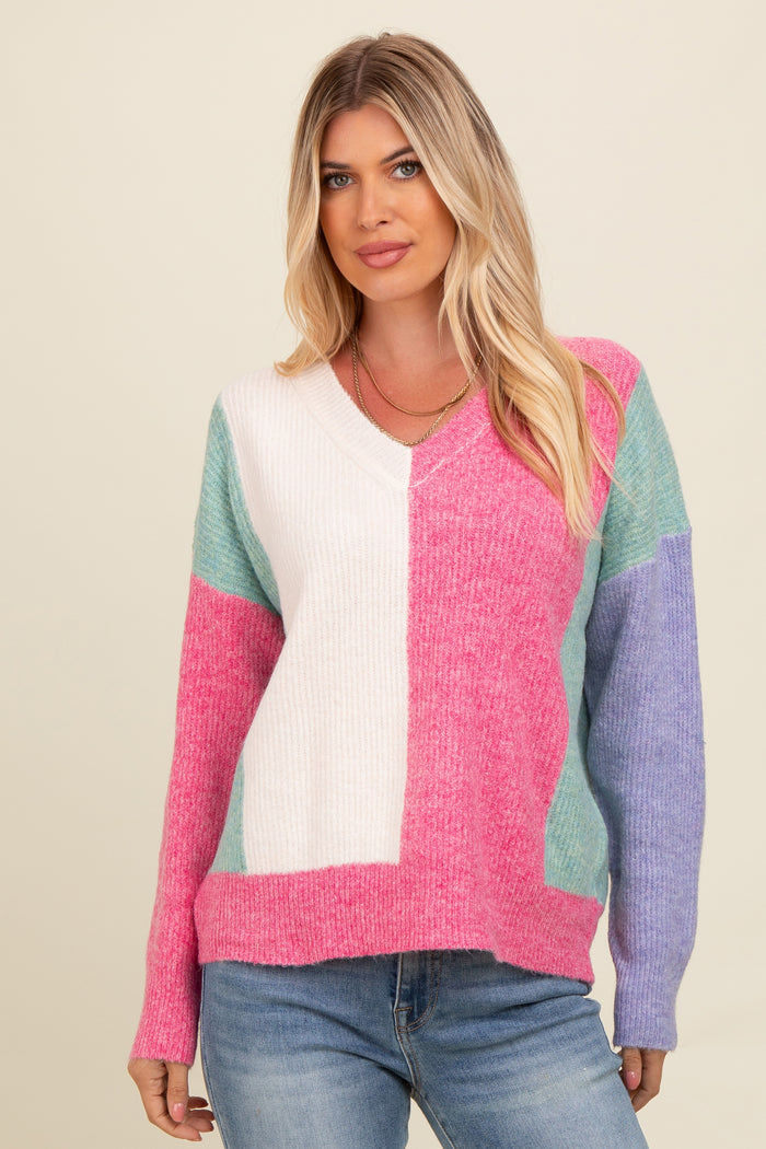 woman wearing a color block v-neck sweater in pink, white, and blue with long sleeves and a relaxed fit
