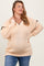 woman wearing a light peach maternity plus oversized sweater with a v-neck and decorative black trim, featuring a visible baby bump