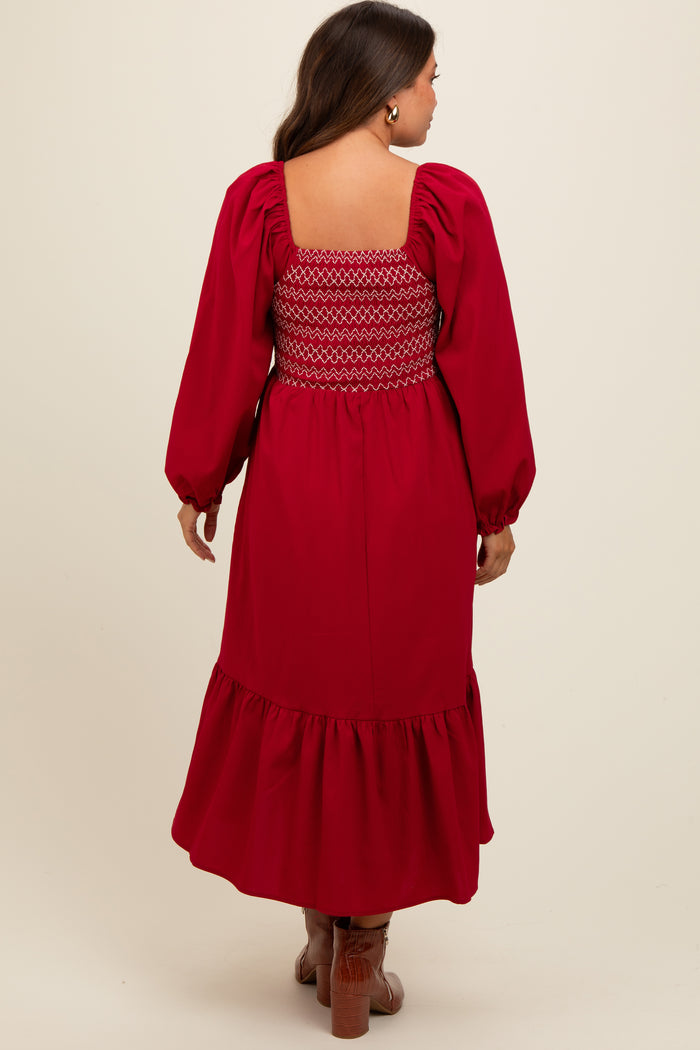 woman wearing a red maternity dress with smocked back and balloon sleeves, featuring a ruffled hem