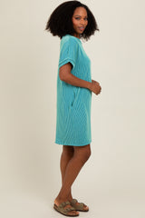 woman wearing a teal striped short sleeve dress with side pockets and brown sandals.