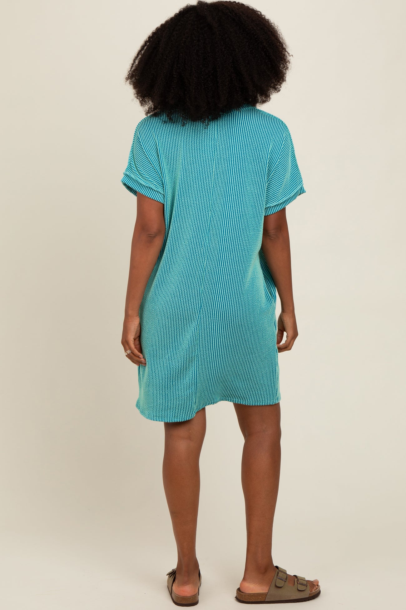 woman wearing a turquoise striped short sleeve dress, seen from the back, with a relaxed fit and casual style