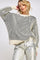 woman wearing a cream and black striped oversized sweater with wide sleeves and metallic silver pants