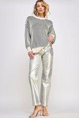 woman wearing a striped oversized sweater and shiny silver wide-leg pants with strappy heels