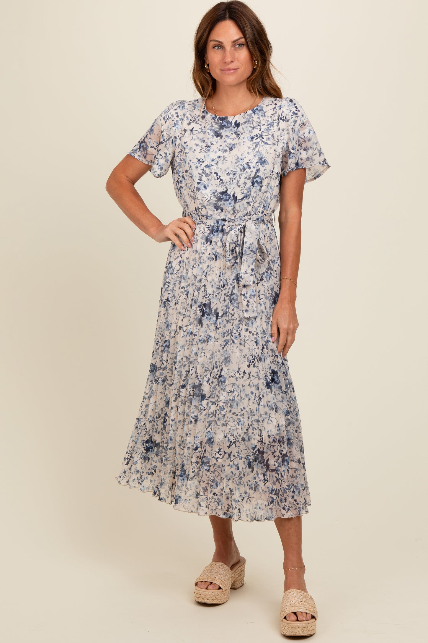 woman wearing a floral print midi dress in shades of blue with short sleeves and a tie waist detail