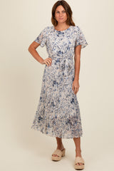 woman wearing a floral print midi dress in shades of blue with short sleeves and a tie waist detail