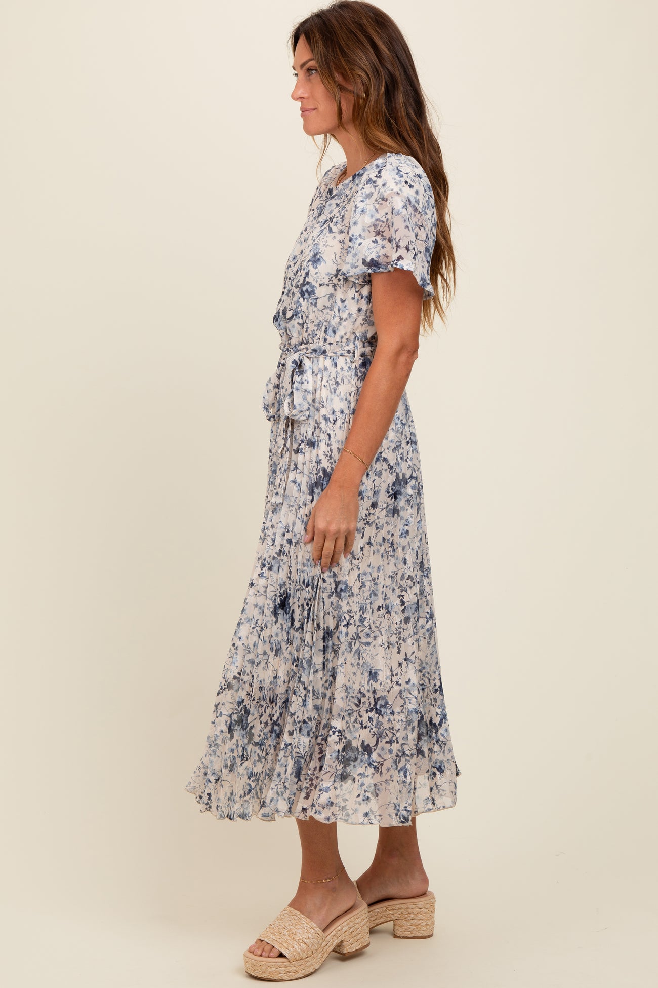 woman wearing a blue and white floral midi dress with short sleeves and a waist tie