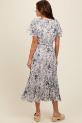 woman wearing a blue and cream floral midi dress with flutter sleeves and keyhole back detail