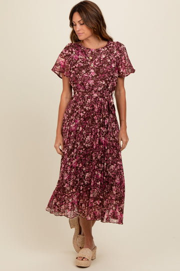woman wearing a burgundy floral midi dress with short sleeves and a tie waist, standing and smiling