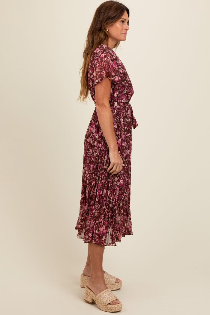 woman wearing a purple floral midi dress with short sleeves and a tie at the waist, styled with platform sandals