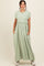 woman wearing a light green maxi dress with short sleeves and a cinched waist, featuring pockets