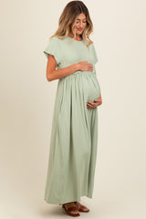 woman wearing a light green maternity maxi dress and holding her baby bump