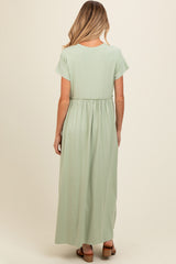 woman wearing a light green maternity maxi dress with short sleeves and an elastic waistband, shown from the back