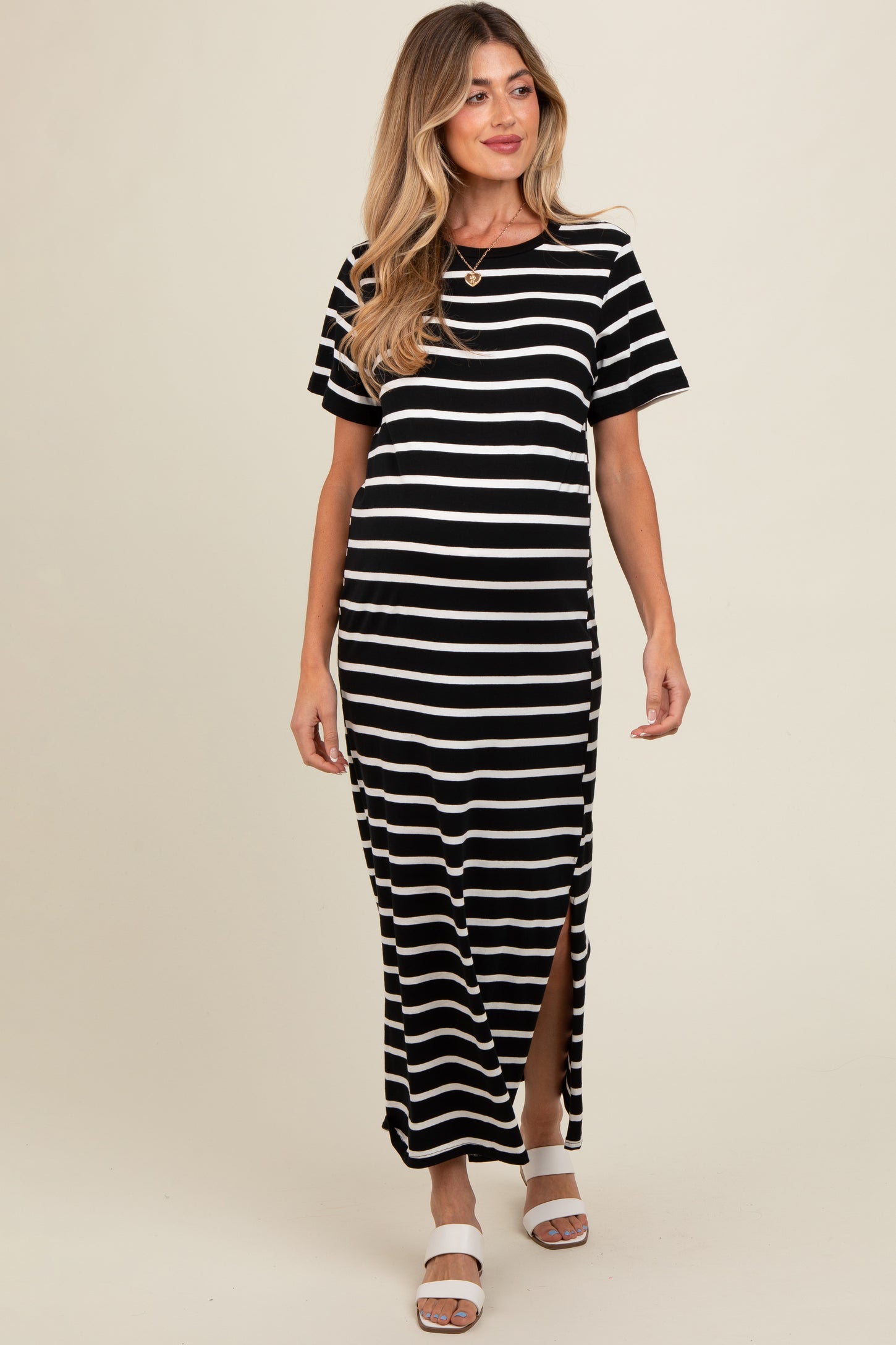 woman wearing a black and white striped maternity maxi dress with short sleeves and side slits