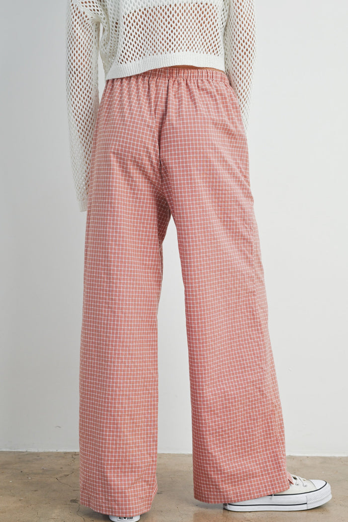 woman wearing a pair of pink checkered wide-leg pants with an elastic waistband and casual sneakers
