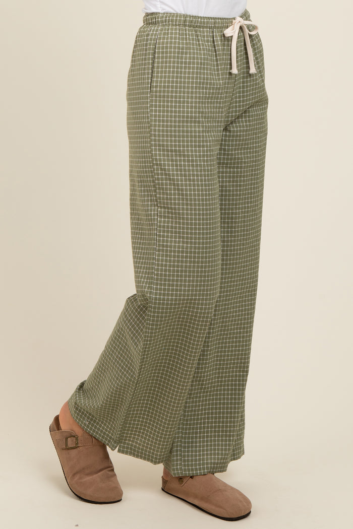 woman wearing green checked wide-leg pants with a drawstring waist and beige slip-on shoes