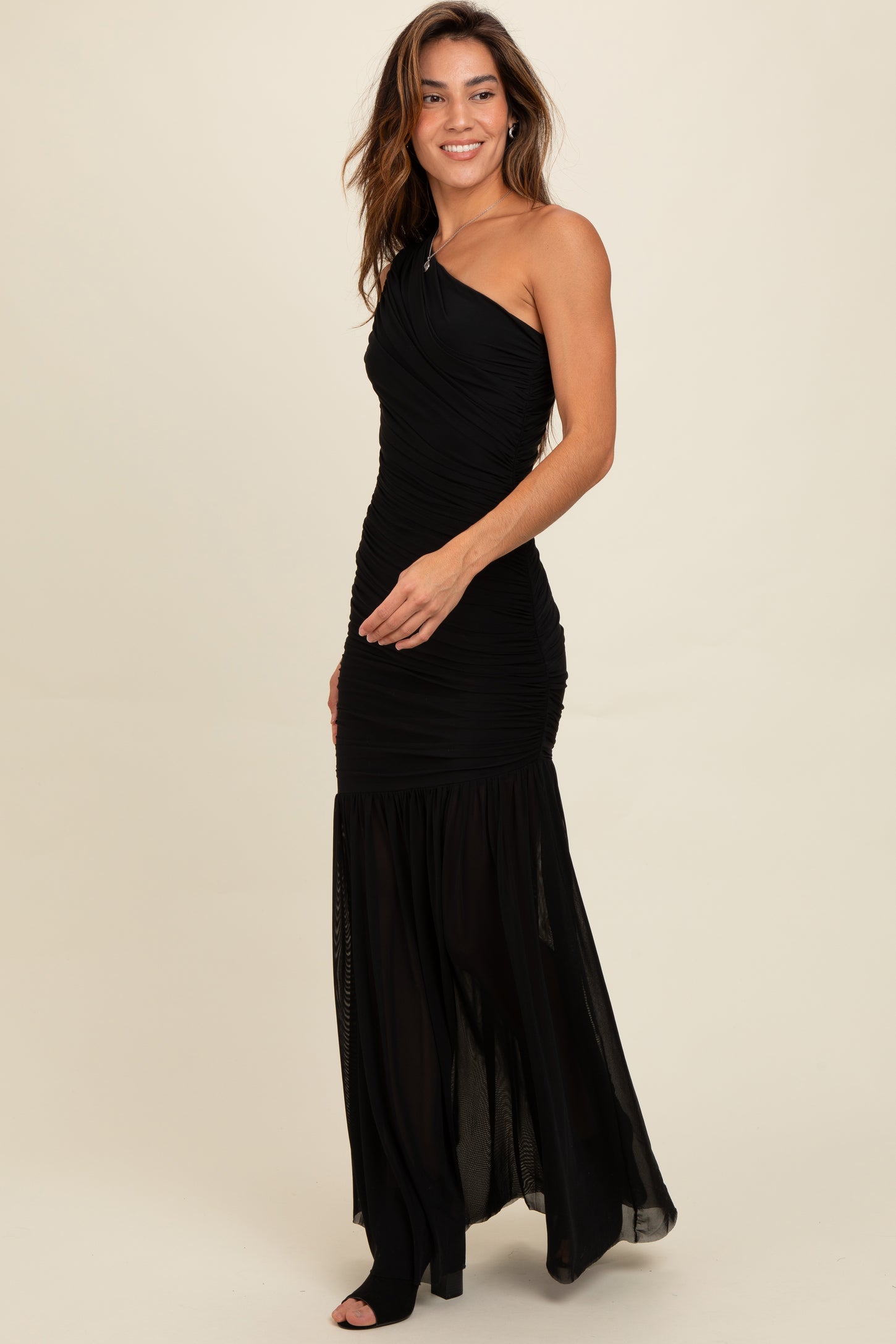 woman wearing a black one-shoulder evening gown with ruched detailing and a flowy skirt