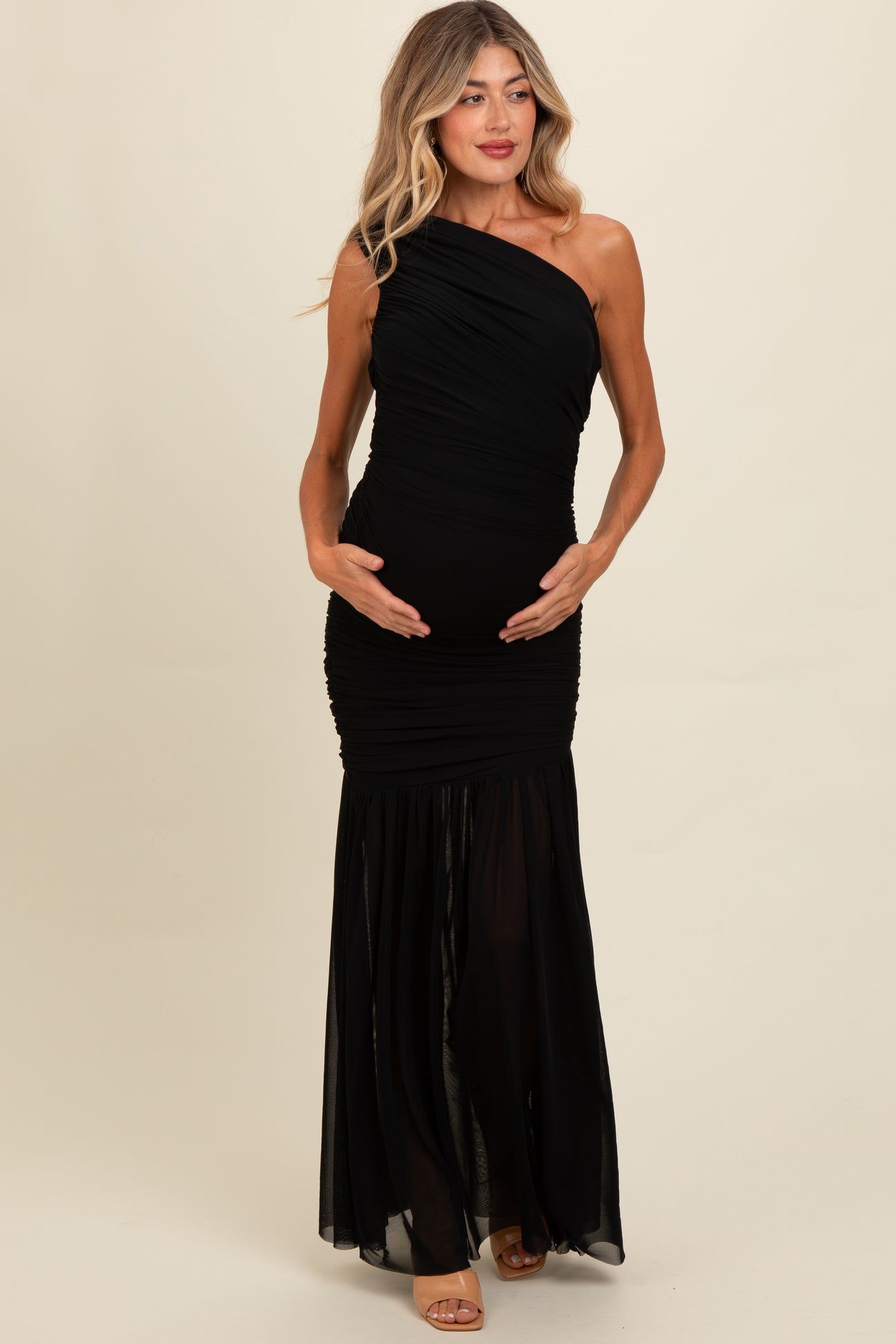 woman wearing a black one-shoulder maternity gown with ruching, holding her baby bump