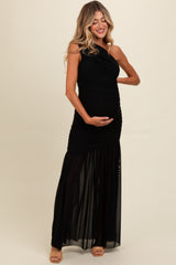 woman wearing a black one-shoulder maternity gown with a flowing skirt and holding her baby bump
