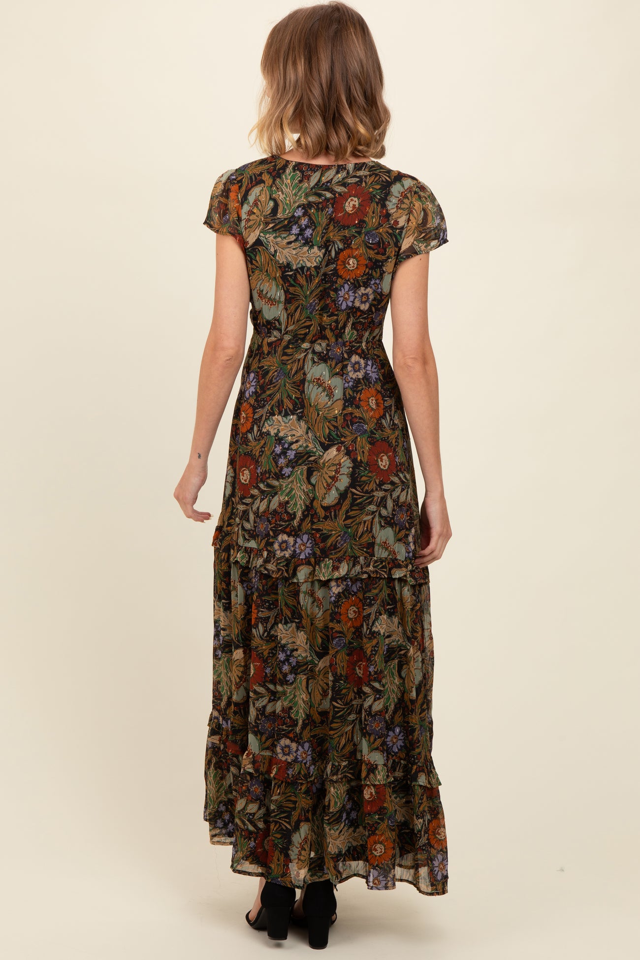 woman wearing a floral black maxi dress with short sleeves and ruffle details, viewed from the back