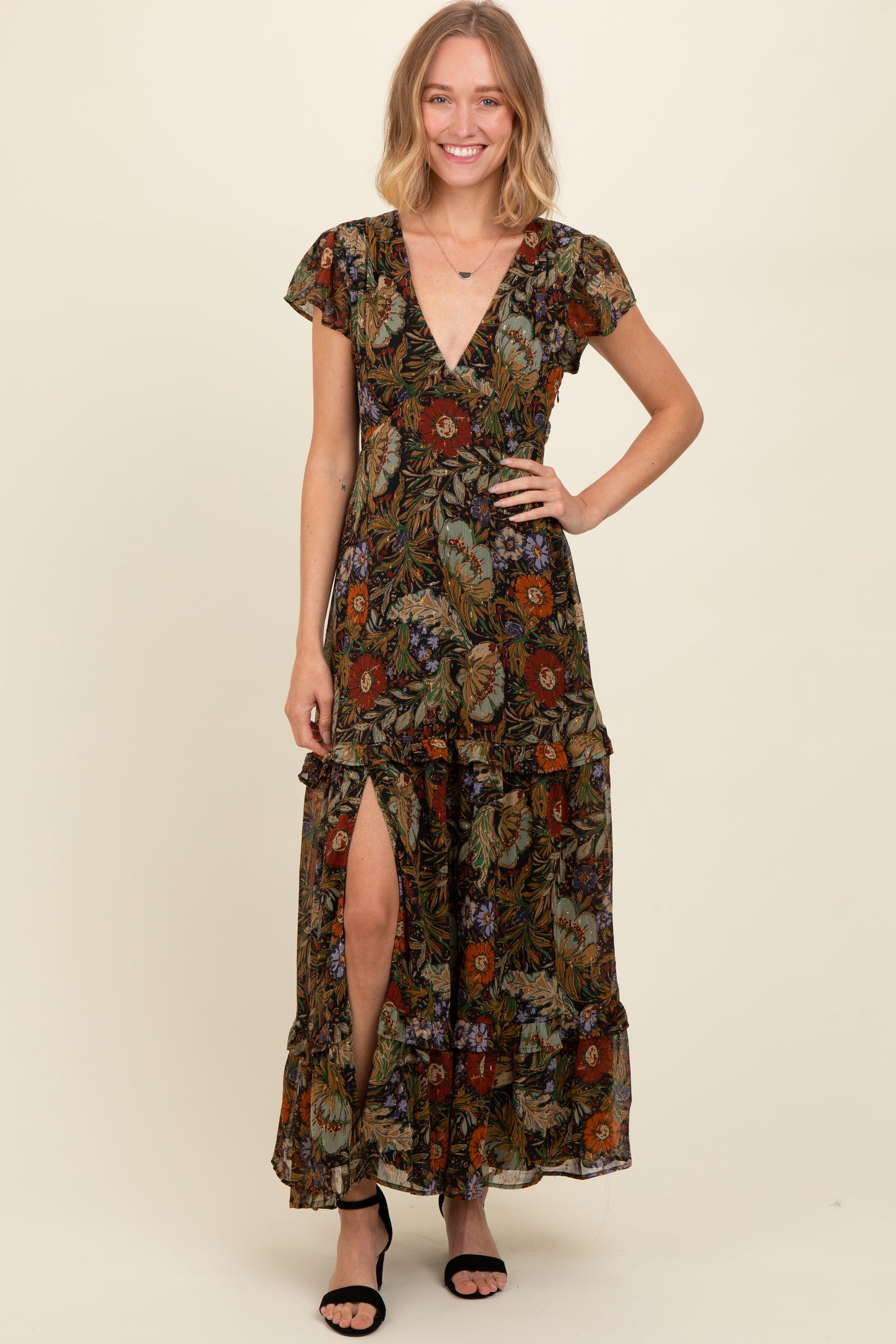 woman wearing a floral maxi dress with a deep v-neck and thigh-high slit, smiling against a neutral background