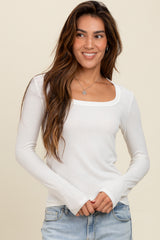 woman wearing a white long sleeve top with a square neckline and light blue jeans