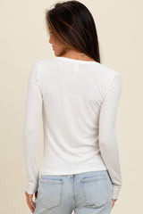 woman wearing a white long sleeve fitted top with a scoop back and light blue jeans