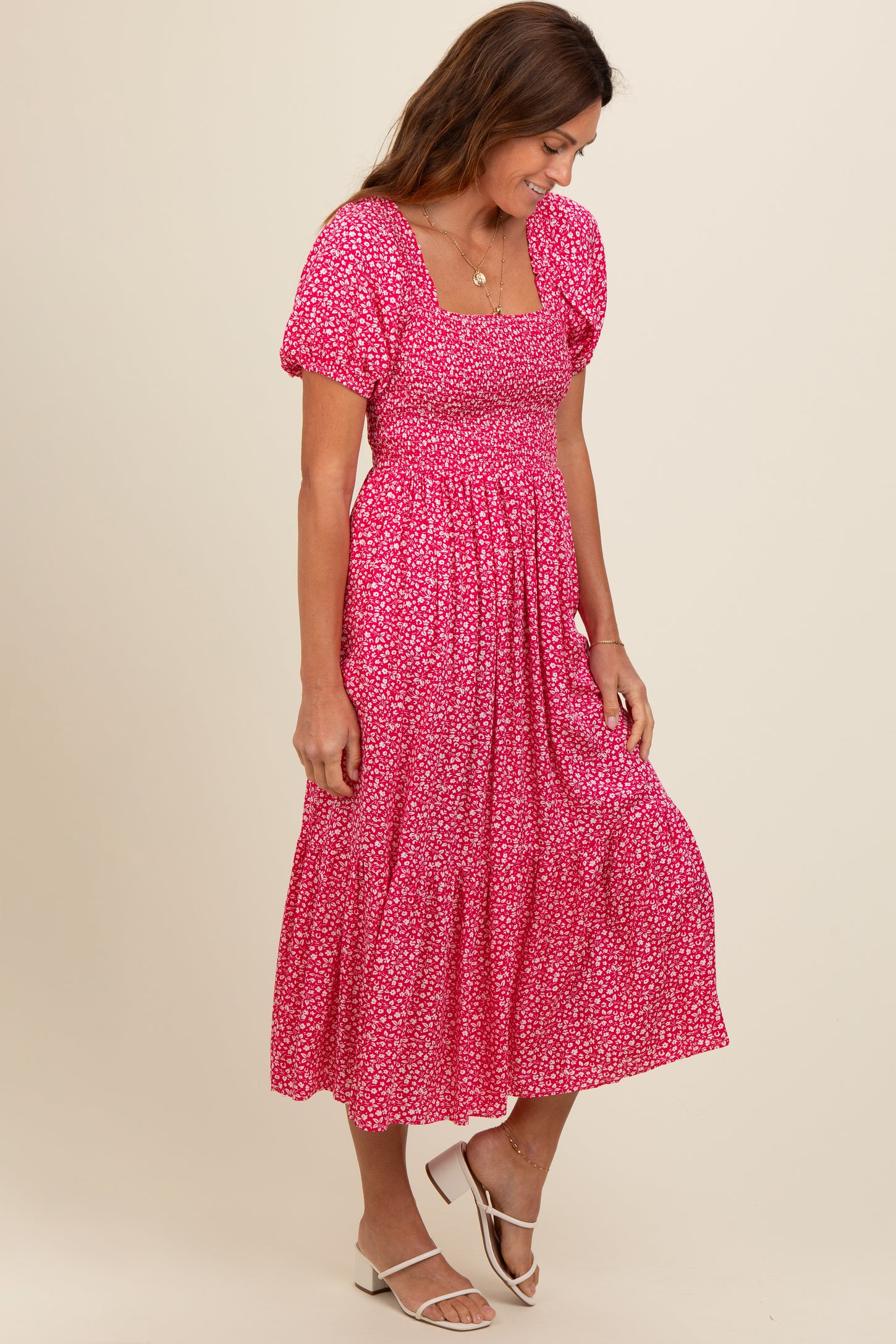 woman wearing a pink floral midi dress with puff sleeves and a smocked bodice