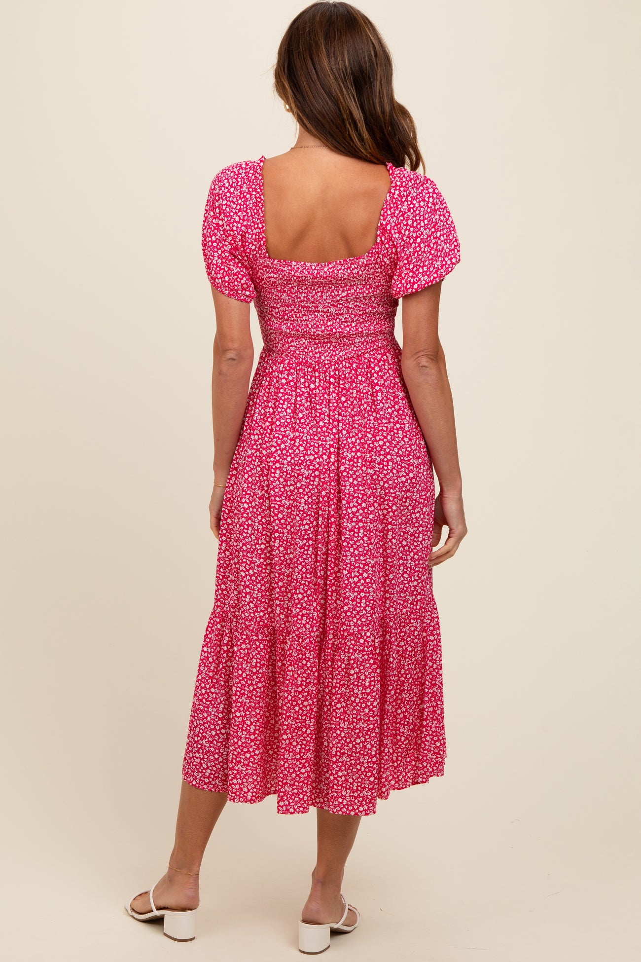 woman wearing a pink floral midi dress with puff sleeves and a tiered skirt, seen from the back