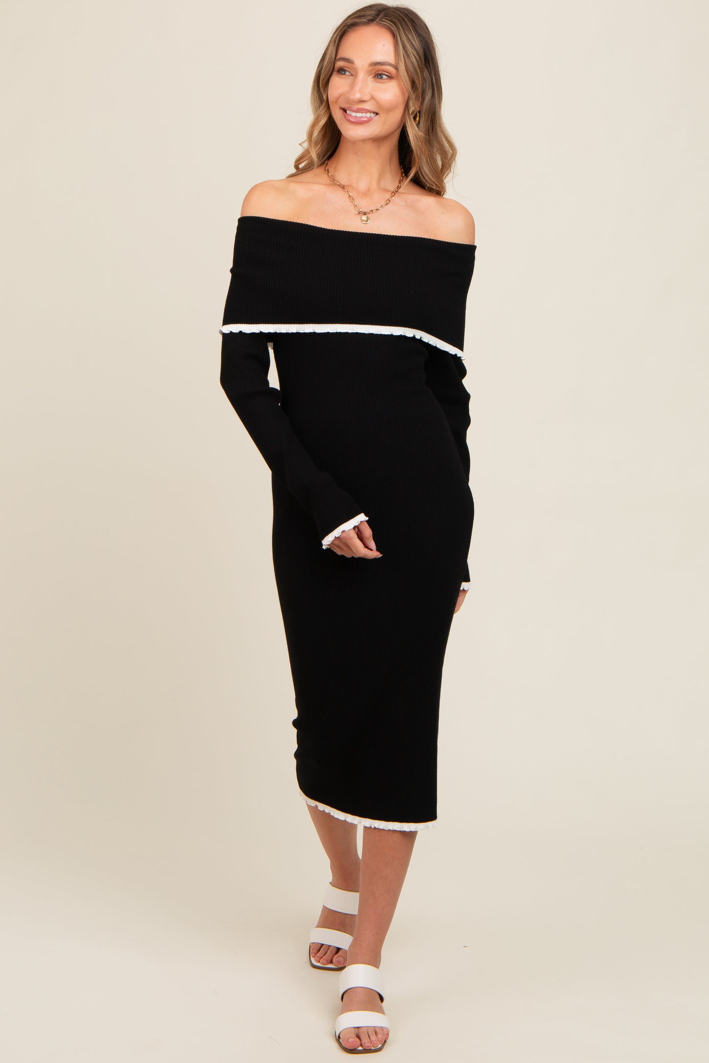 woman wearing a black off-the-shoulder ribbed midi dress with white trim and long sleeves