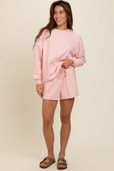 woman wearing a pink checkered loungewear set with long sleeve top and shorts