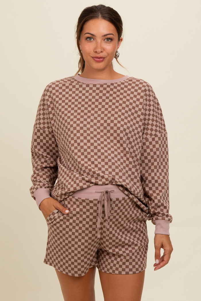 woman wearing a brown checkered maternity loungewear set consisting of a long sleeve top and matching shorts