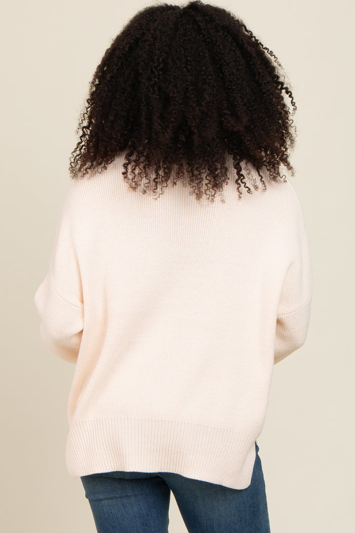 woman wearing a light pink oversized sweater from the back with a relaxed fit and ribbed hem